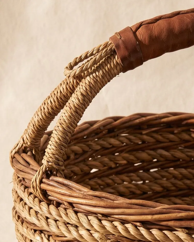 A close view of a coiled seagrass gathering basket with tight regular coiling on a warm paper sweep.