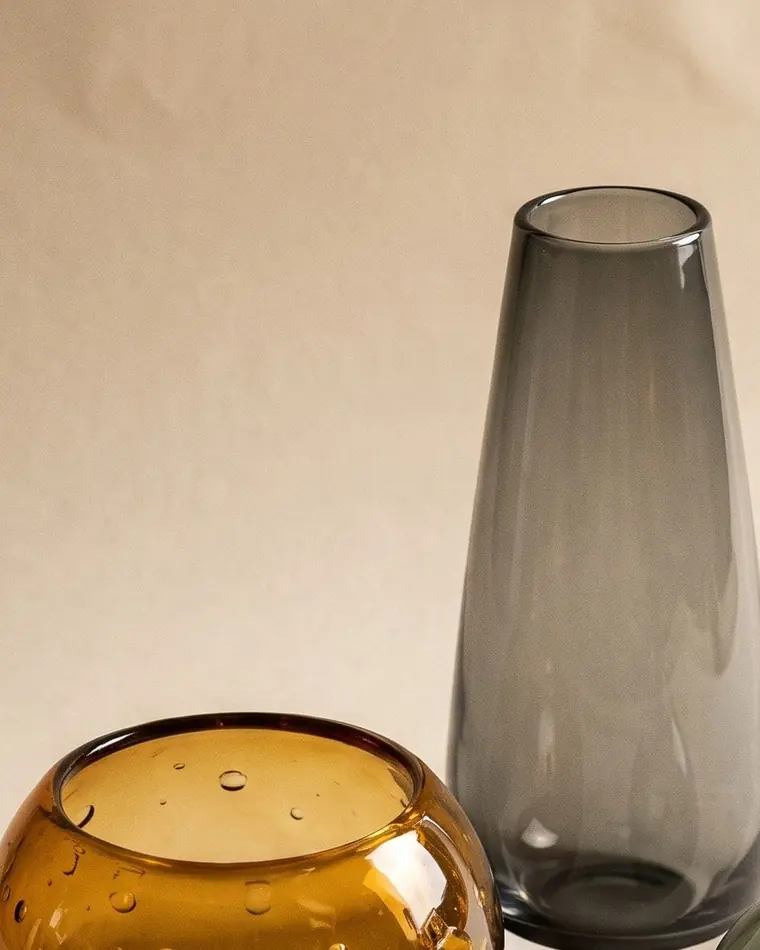 A close view of an amber hand-blown glass bubble bowl throwing warm caustic light onto a warm paper sweep.