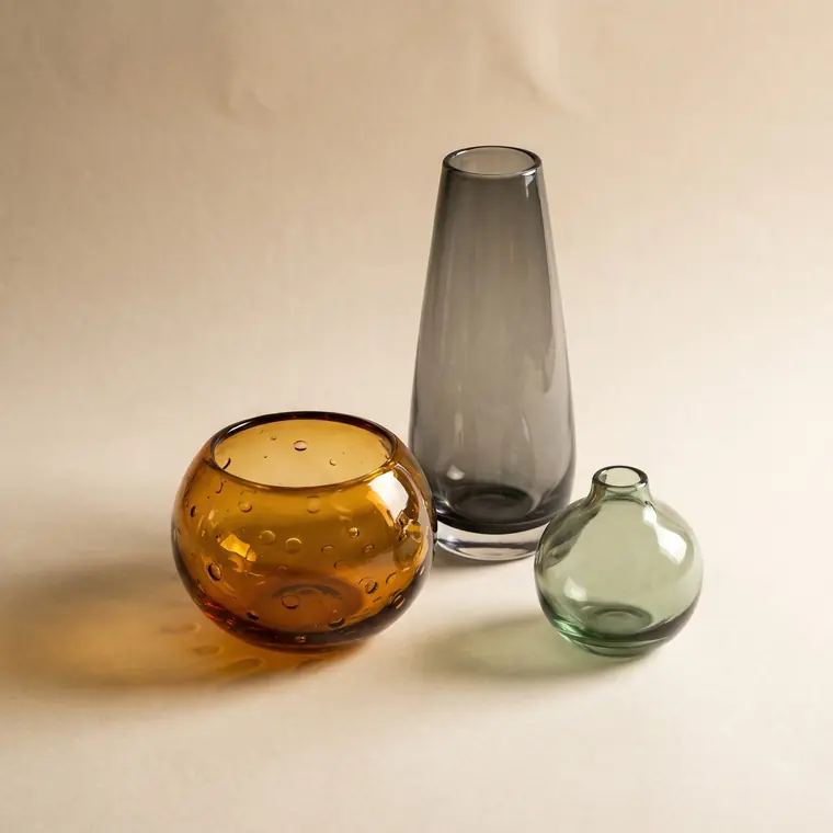 A close view of an amber hand-blown glass bubble bowl throwing warm caustic light onto a warm paper sweep — upper detail.